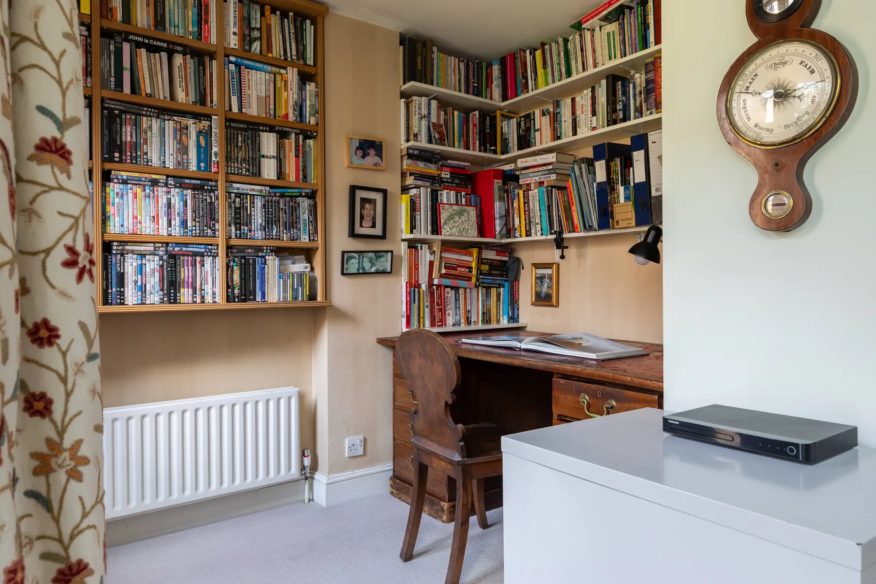 A home study with bookshelves, a wooden desk, and a television on a cabinet.