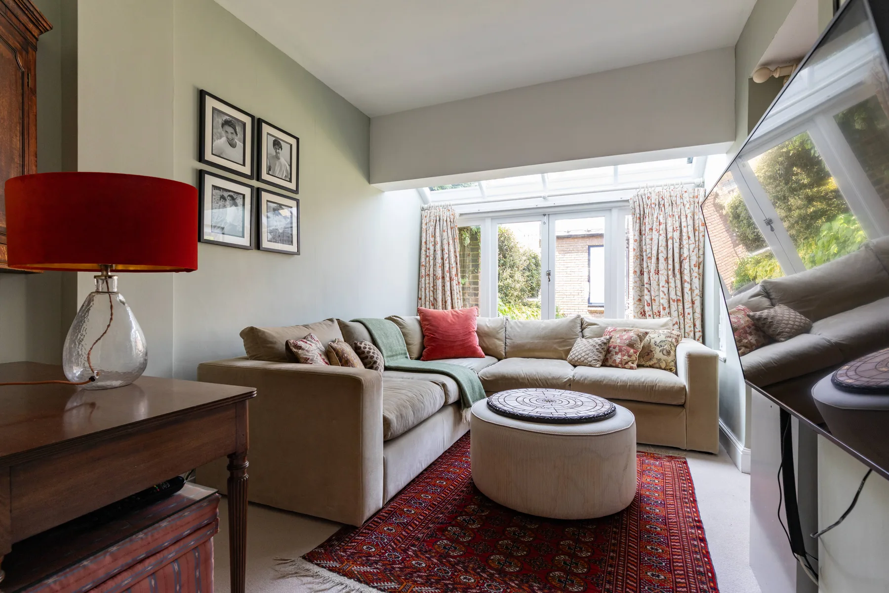 A bright living room with a sectional seating area and a round ottoman.