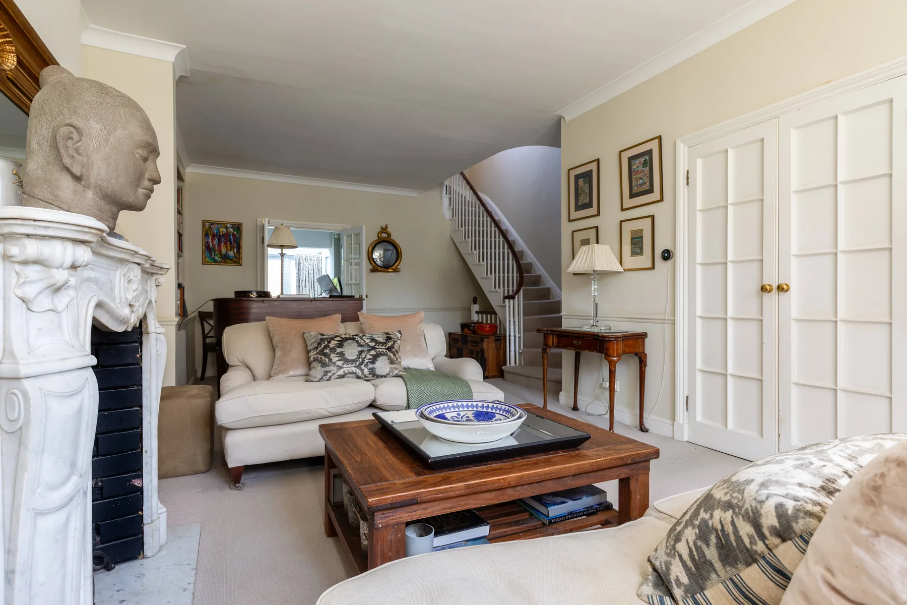 A living room with seating, a wooden coffee table, and a staircase.