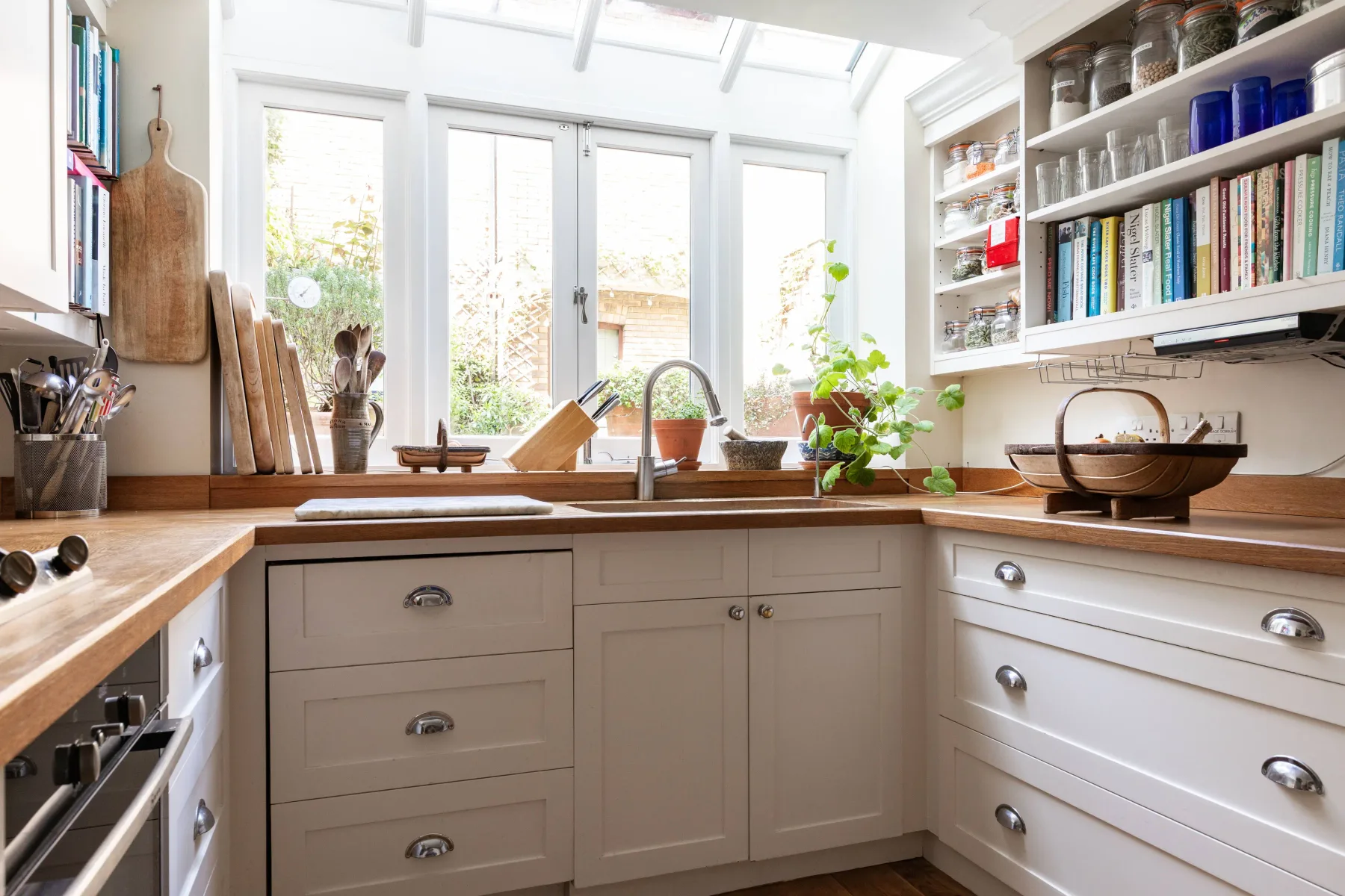 A bright kitchen with white cabinets, wooden countertops, and a window over the sink.