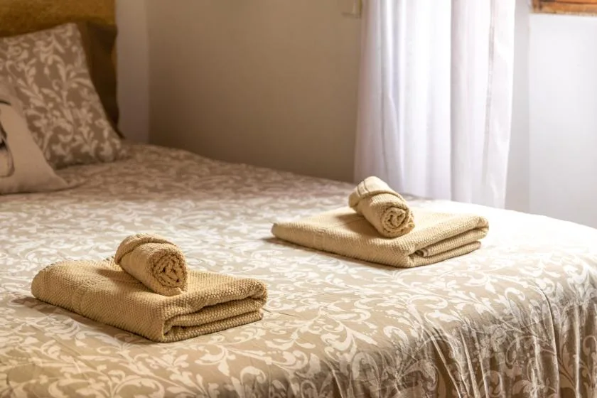 A bedroom with a patterned bedspread and folded towels.