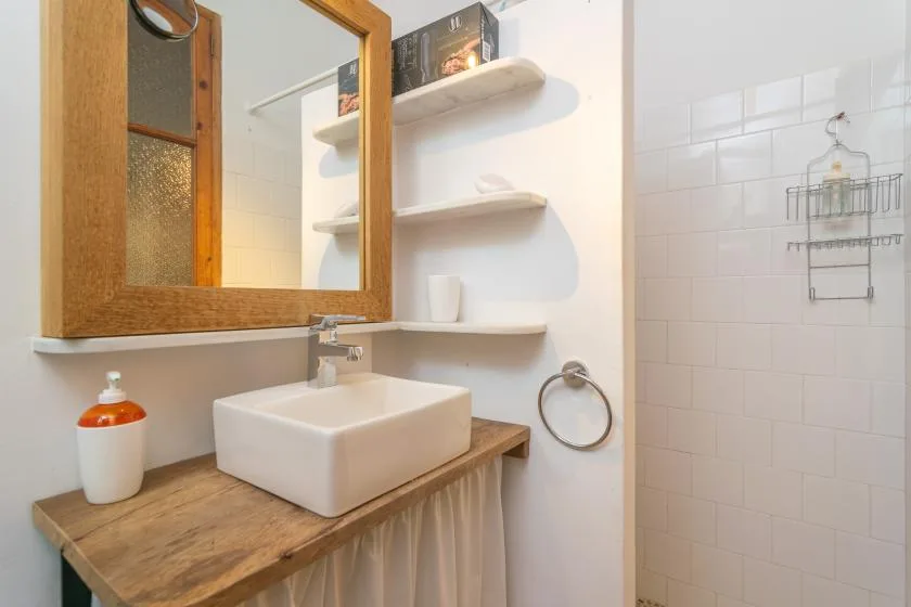 A bathroom vanity with a vessel sink sits beside a tiled shower area.