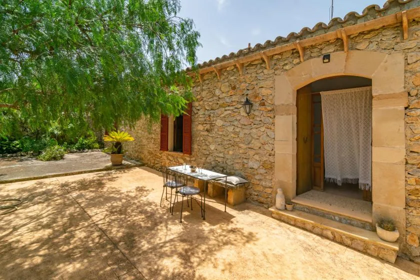 A stone courtyard with a shaded patio table beside an arched doorway.