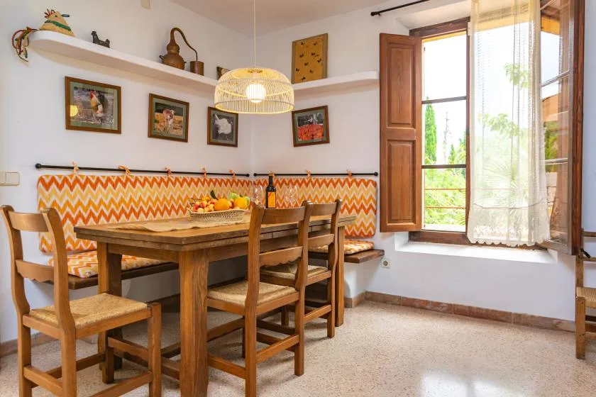 A dining area with a wooden table, bench seating, and an open window.