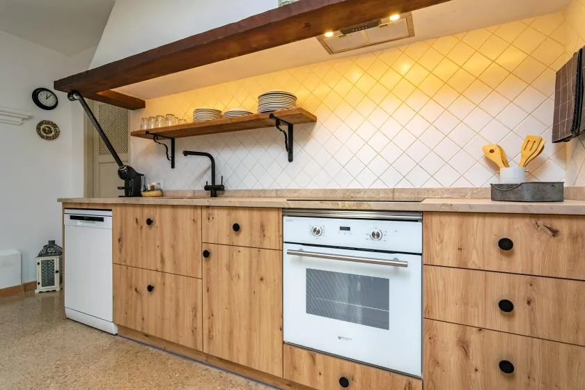 A kitchen with wooden cabinets, a countertop, and a white oven.