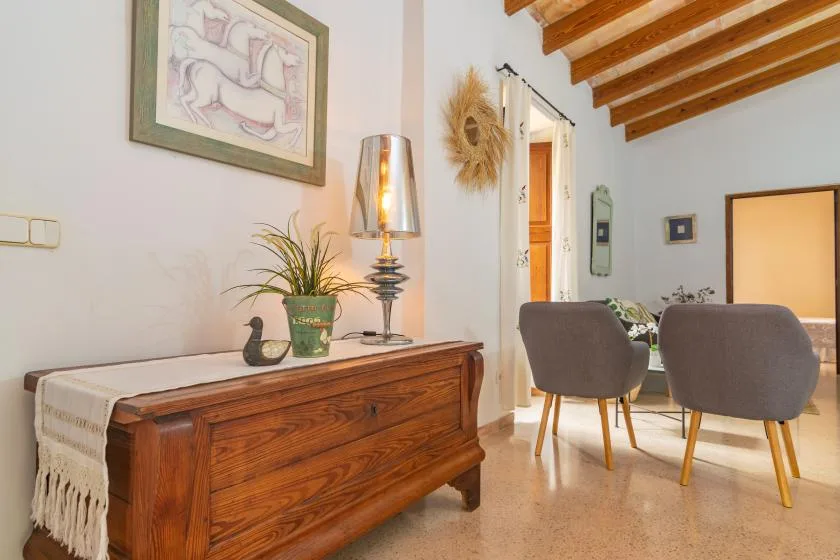 A dining area with upholstered seating, a wooden sideboard, and exposed ceiling beams.