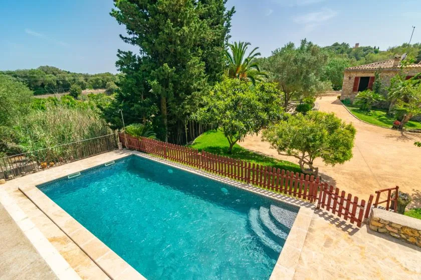 An outdoor swimming pool beside a fenced garden and landscaped grounds.