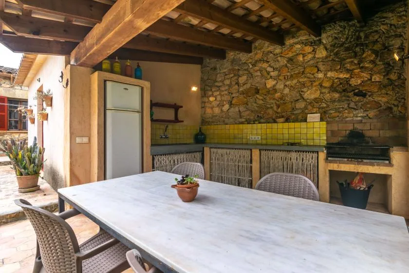 A covered outdoor dining area with a long table and a stone wall.