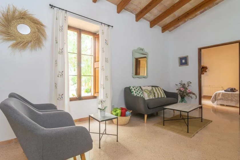 A bright living room with gray seating, a coffee table, and a large window.
