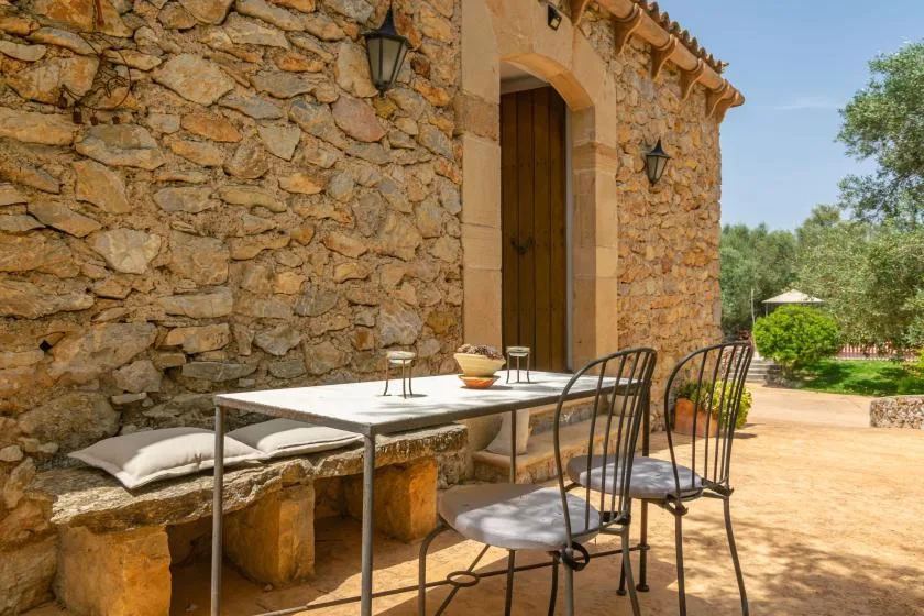 An outdoor dining area beside a stone wall, with a table and chairs.