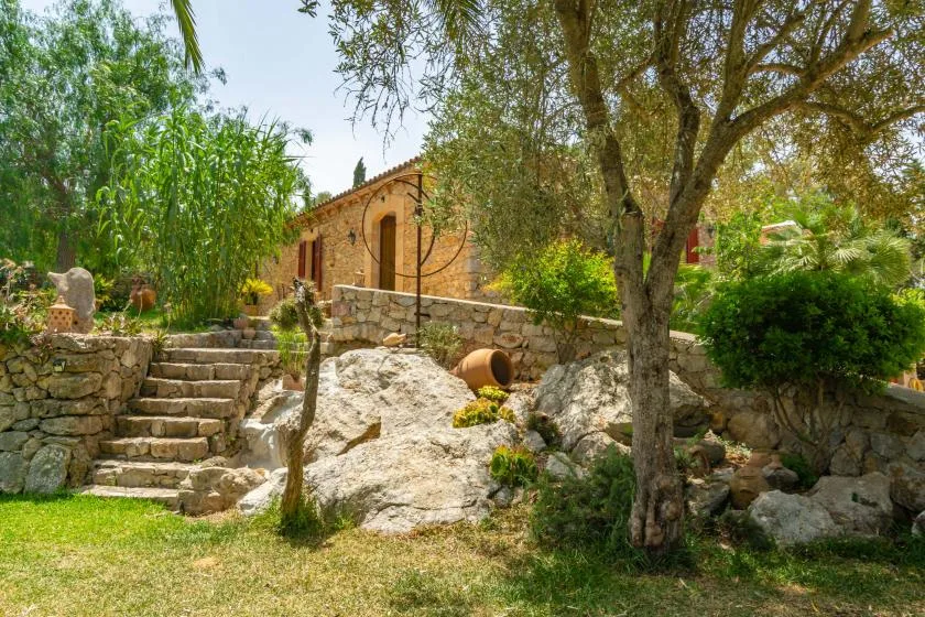 A stone garden with a short staircase, trees, and a small stone building.