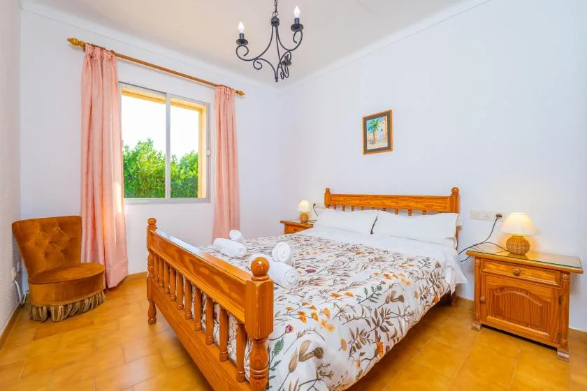 Un dormitorio con una cama de madera, ropa de cama estampada y una ventana con cortinas rosas.