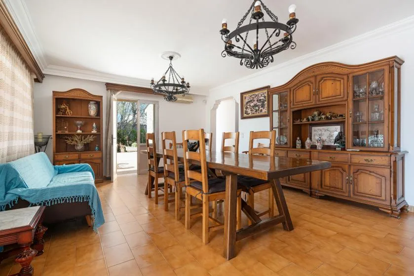 Un comedor con una mesa larga de madera y sillas junto a un gran mueble vitrina.