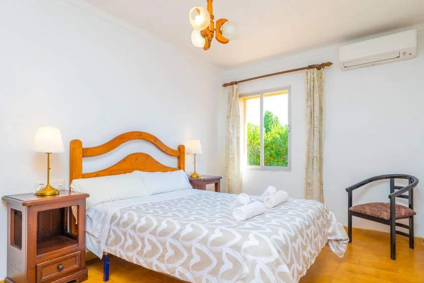 Un dormitorio con una cama doble, mesitas de noche y una ventana con vistas a la vegetación.