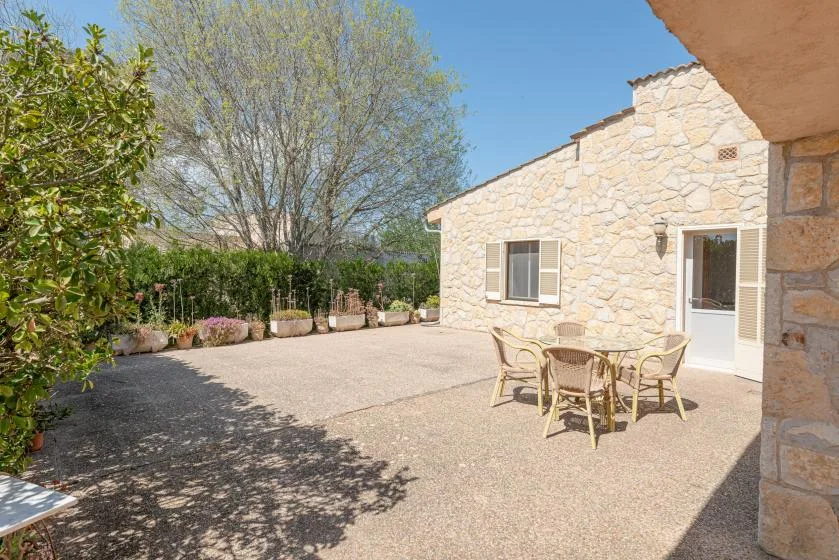 Un edificio de piedra da a un patio soleado pavimentado con asientos al aire libre.