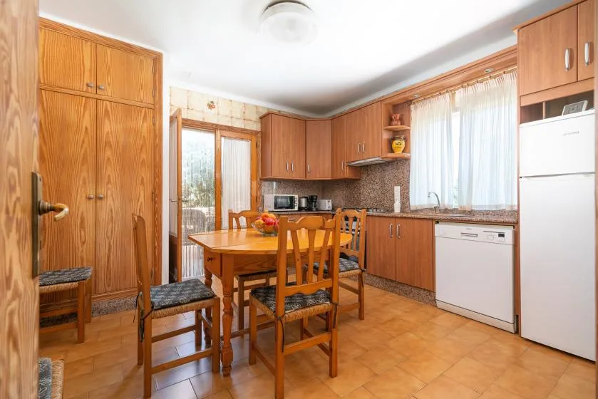 Una cocina y zona de comedor con armarios de madera, una mesa y sillas.