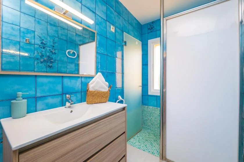 Un baño con un lavabo blanco y paredes de azulejos azules.