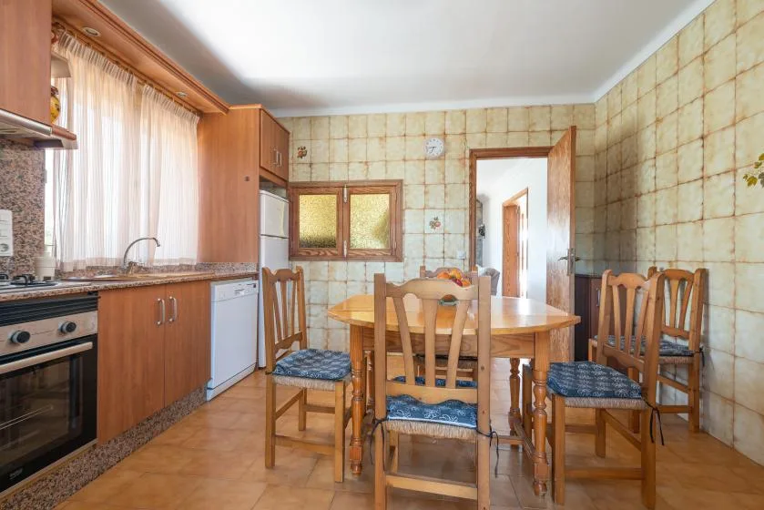 Una cocina y comedor alicatados con una mesa de madera y sillas.