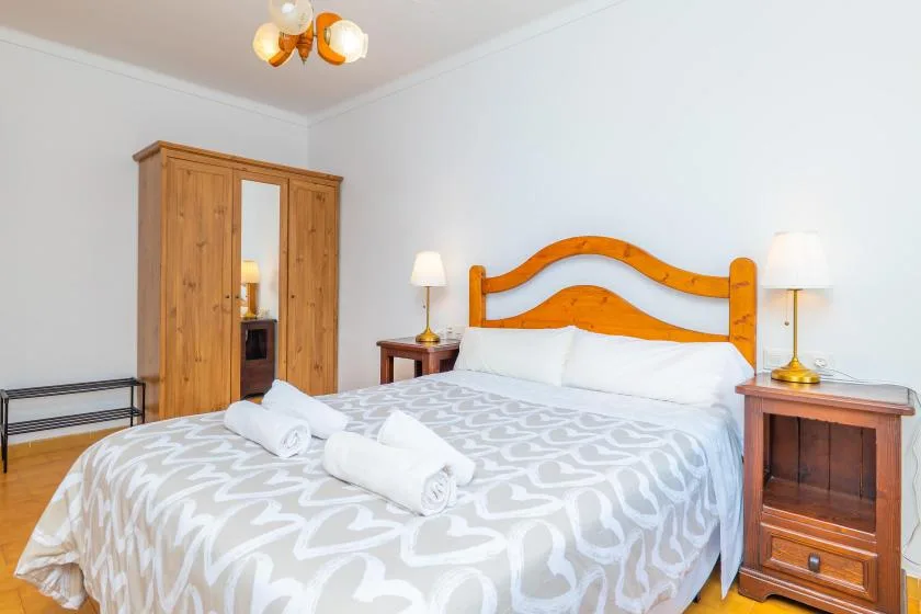 Un dormitorio con una cama de madera, ropa de cama estampada y un armario.