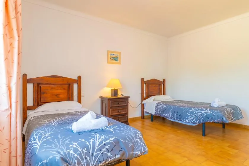 Un dormitorio con dos camas, una mesita de noche y una lámpara encendida.
