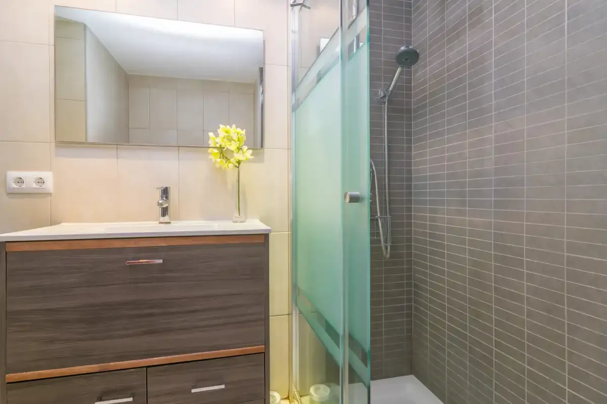 A bathroom with a sink, mirror, and glass shower.