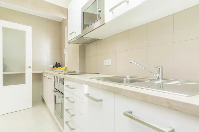 A bright kitchen with white cabinets, a countertop, and a sink.