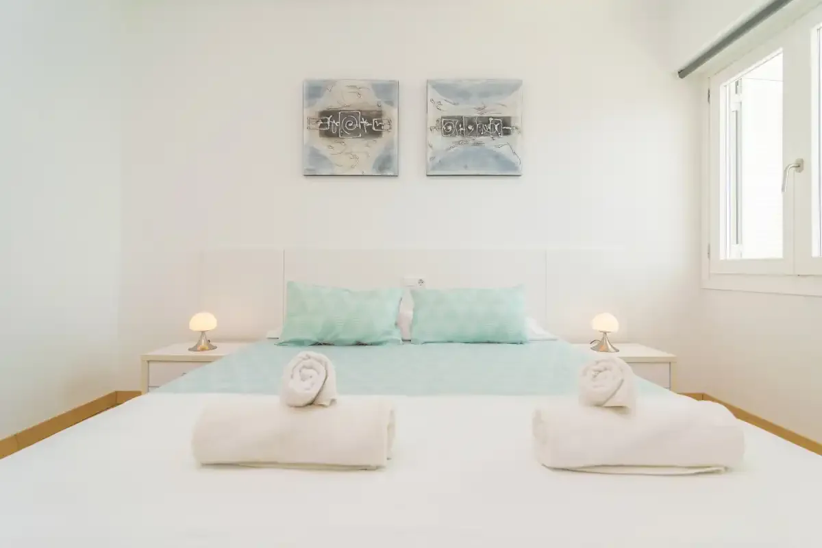 A bright bedroom with a bed and pale aqua bedding.