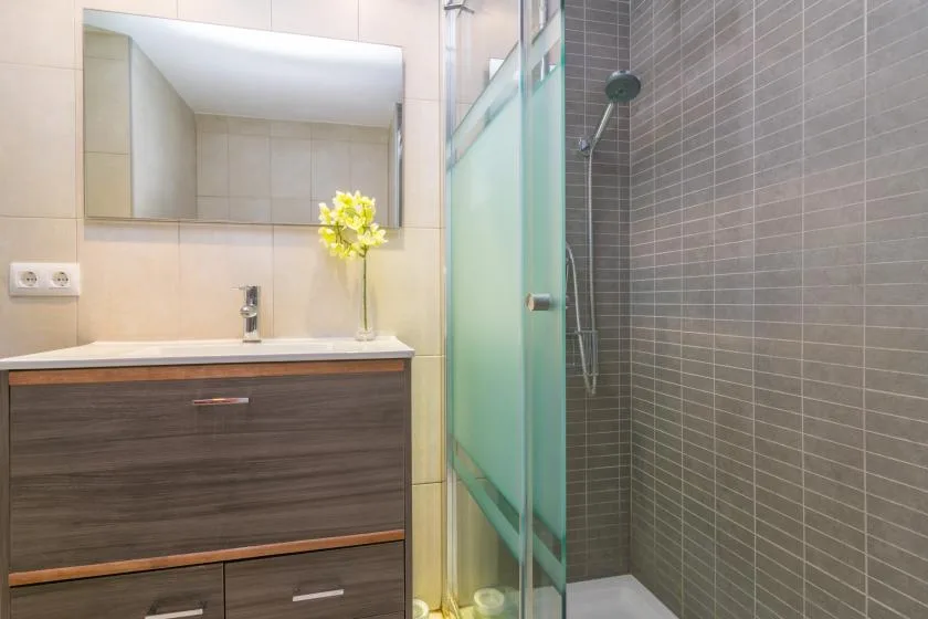 A bathroom vanity with a sink sits beside a glass shower.