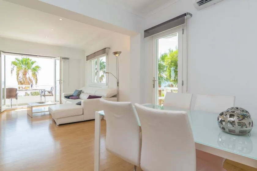 A bright living and dining area with white seating and large windows.