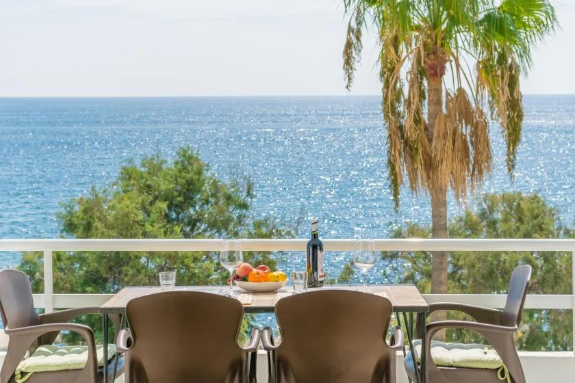 An outdoor dining area overlooks the sea, with a table beside the railing.