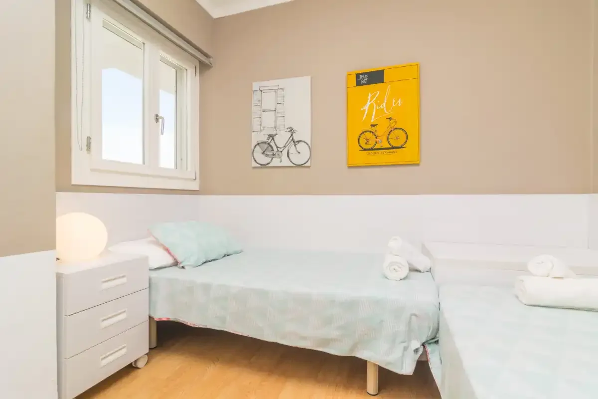 A bedroom with two beds beneath bicycle-themed wall prints.