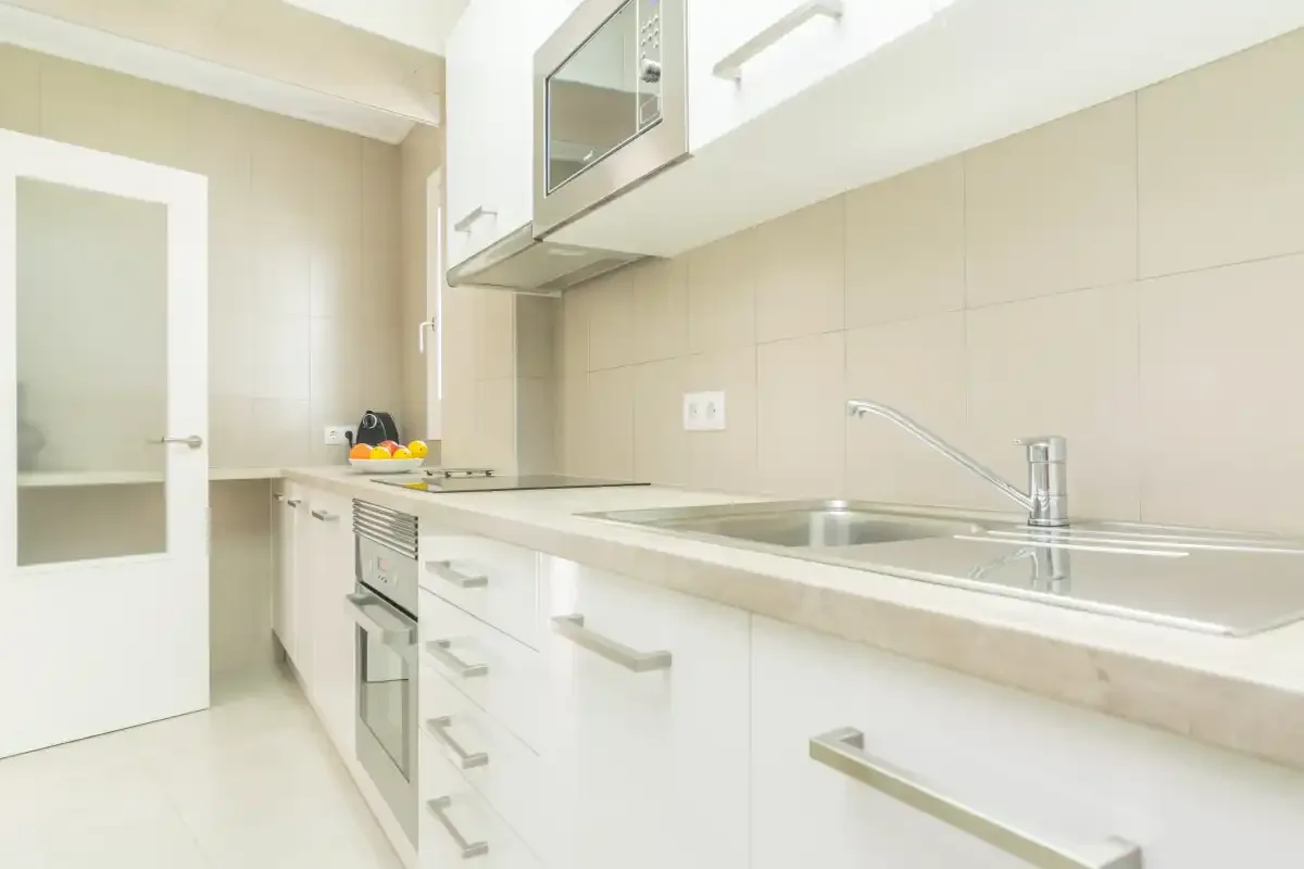 A bright kitchen with white cabinetry and a long countertop.