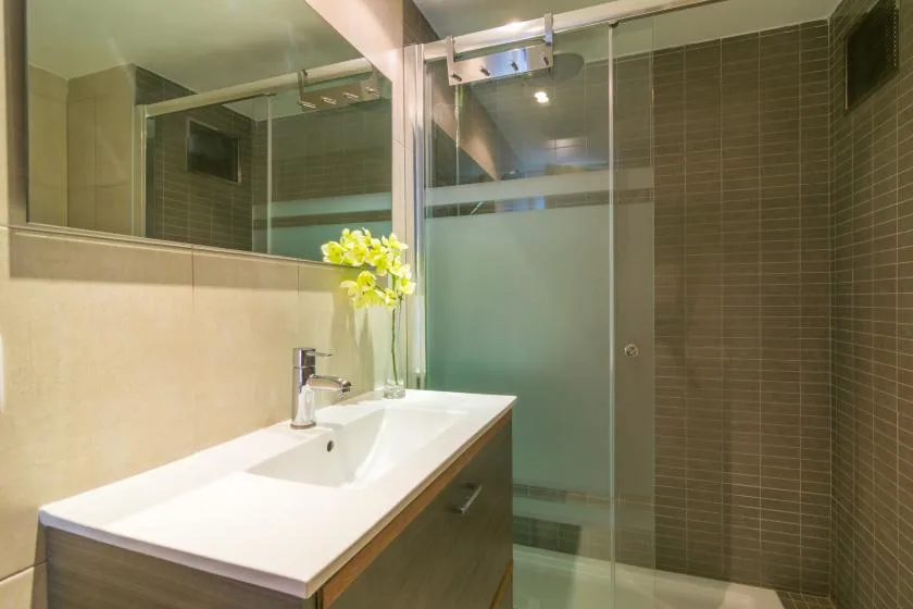 A bathroom with a long vanity and a glass shower.