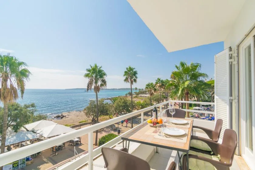A balcony dining area overlooks the water and palm trees.