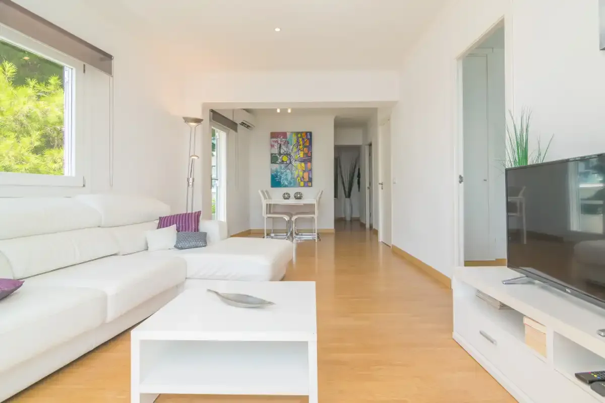 Bright living room with white seating, a coffee table, and a television.