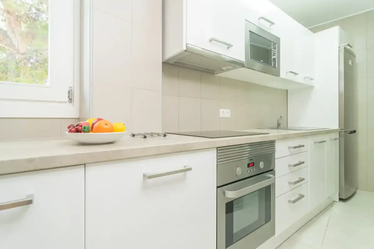 A bright kitchen with white cabinets, a countertop, and built-in appliances.