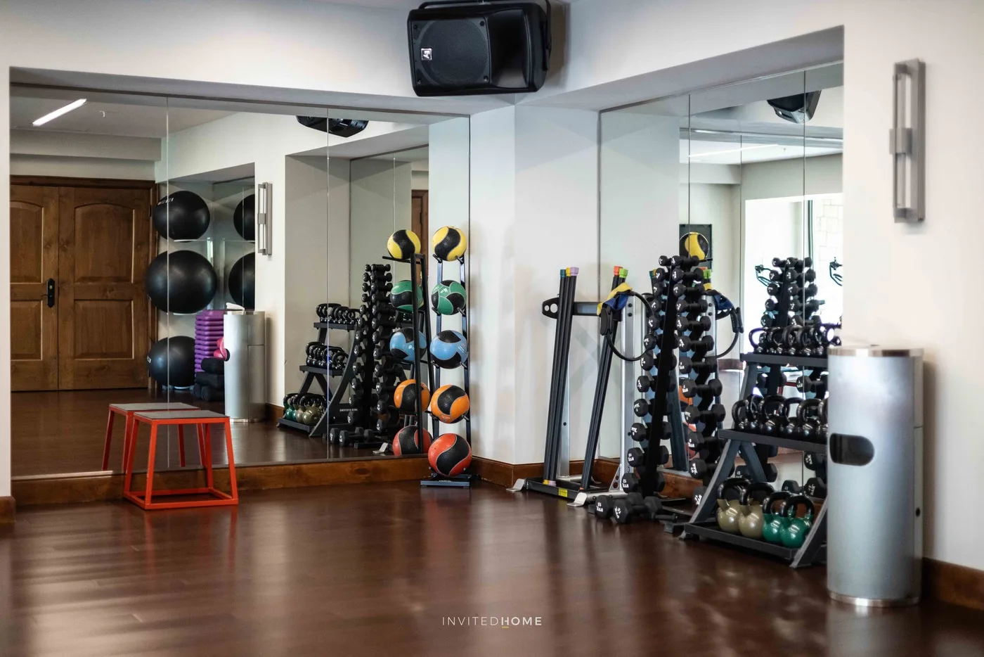 Un gimnasio con espejos, equipo de ejercicio y suelo de madera despejado.