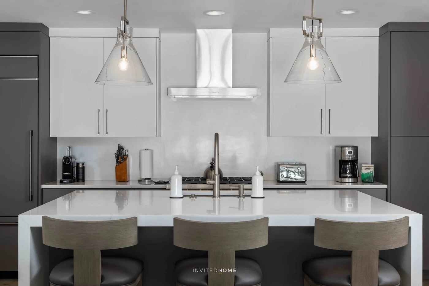 Una cocina moderna con una isla central y tres asientos.