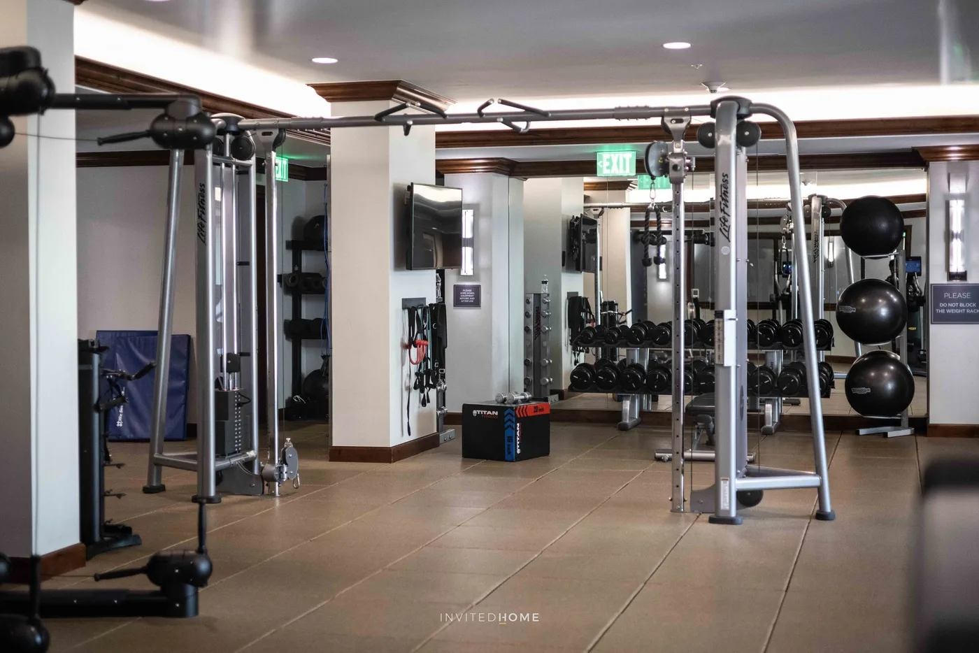 Una sala de entrenamiento con máquinas de ejercicio, pesas y paredes con espejos.