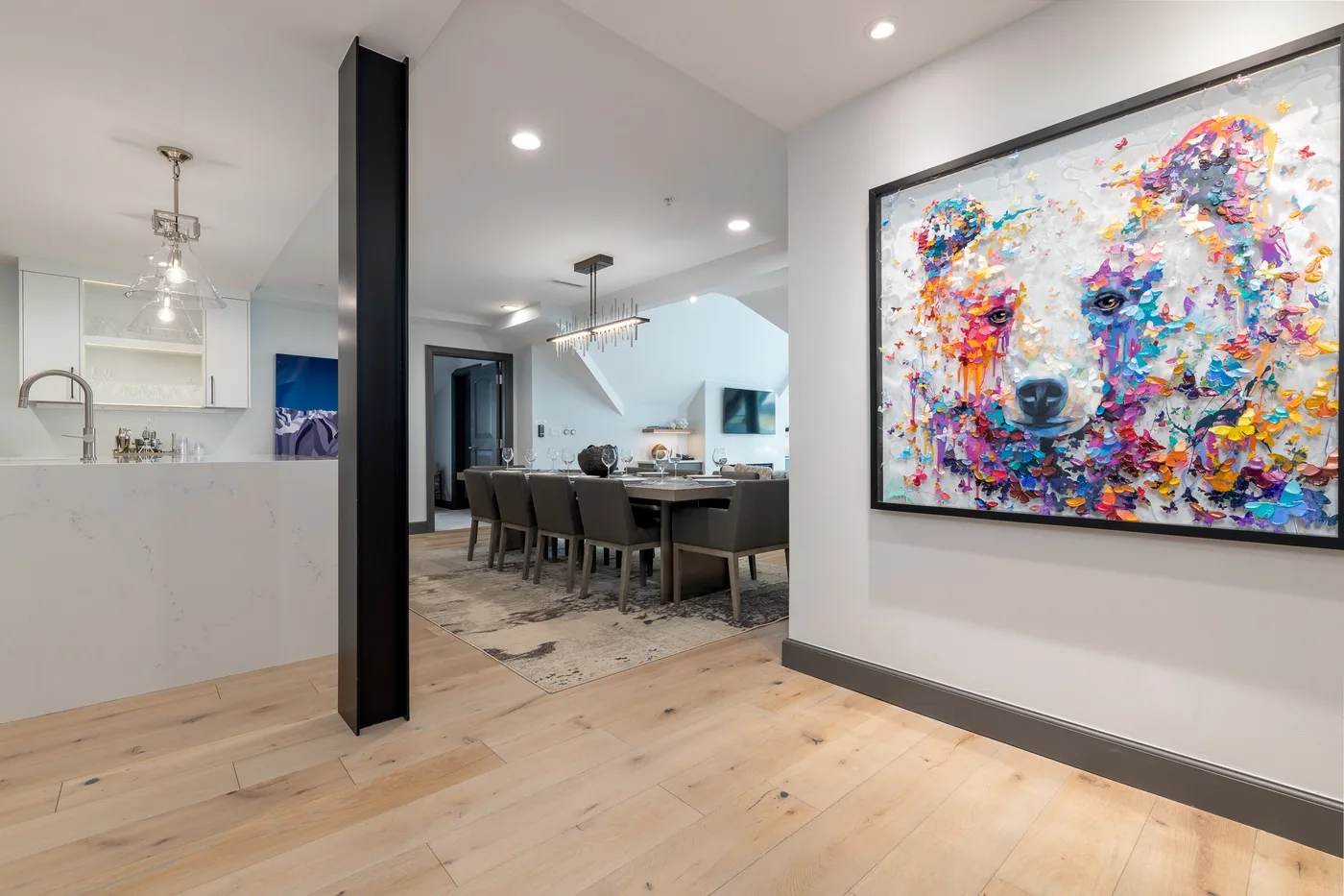 Comedor de concepto abierto con una mesa larga y una obra colorida en la pared.