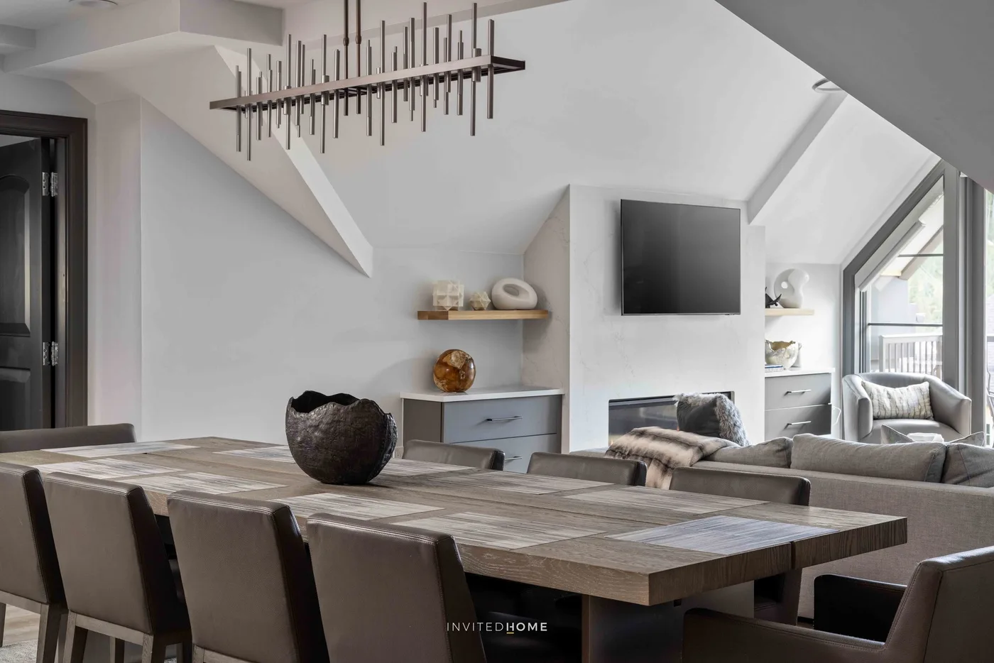 Un comedor y sala de estar modernos, con una mesa larga y asientos junto a grandes ventanas.