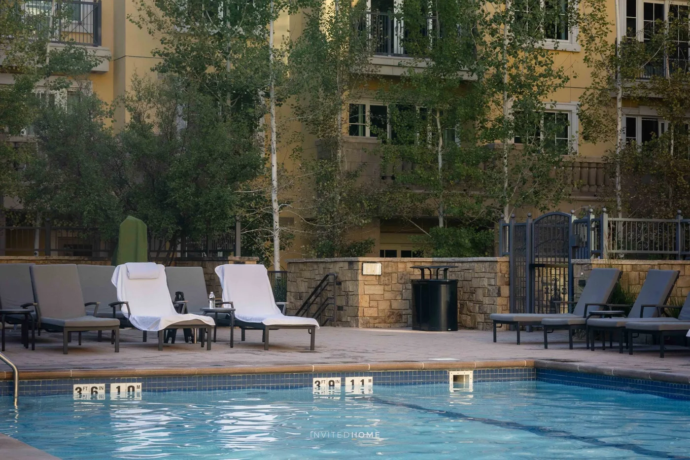 Una piscina al aire libre con asientos de descanso junto a un patio ajardinado.