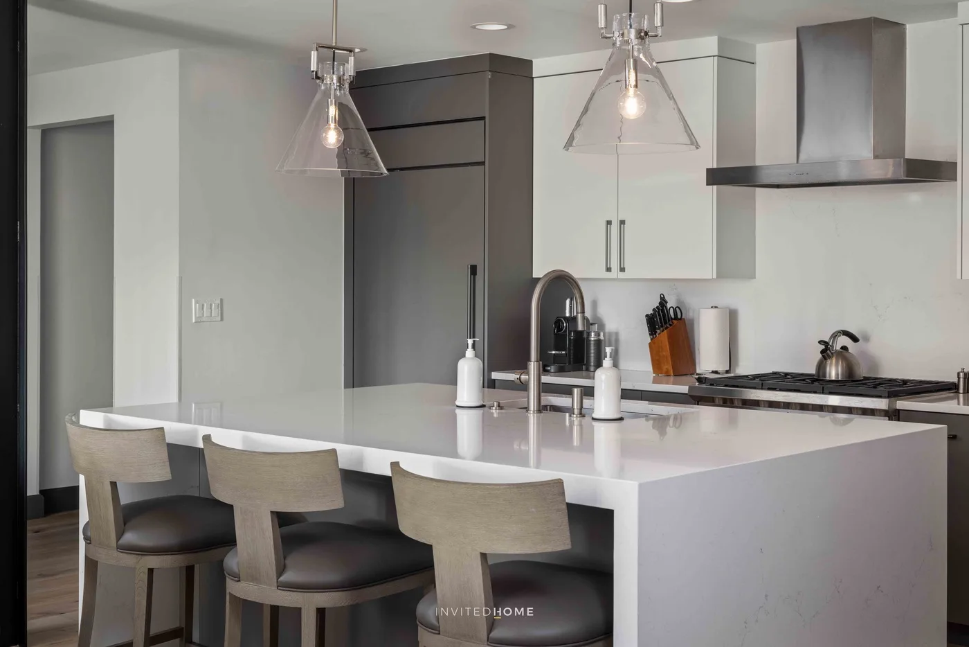 Una cocina moderna con una isla grande, asientos de barra y luces colgantes.