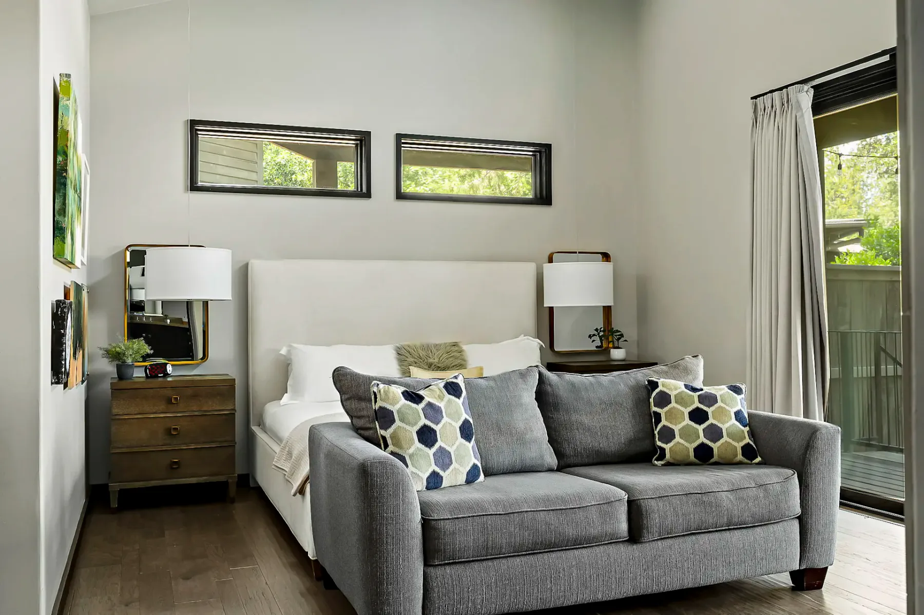 A bedroom with a bed and gray seating in front of it.