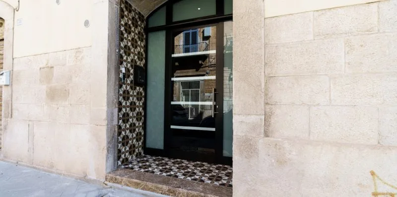 A dark glass entrance is set into a pale stone facade.