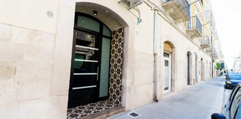 A street-side building entrance with a dark door and patterned tile surround.