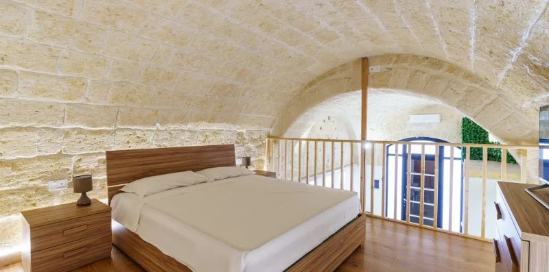 A bedroom with a large bed beneath a curved stone ceiling.