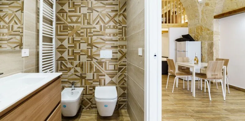 A bathroom with a bathtub and patterned tile beside a dining area.
