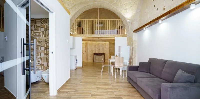 A living room with a gray sofa and an arched upper-level opening.