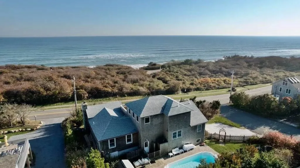 Una casa costera con piscina exterior está junto a una carretera con vistas al mar.
